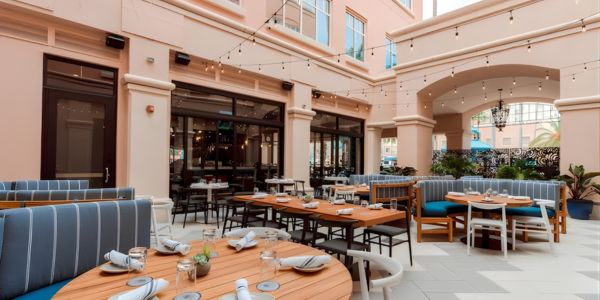 Outdoor dining courtyard at American Social in Boca Raton, Florida, with table seating, string lights, and surrounding architectural columns.
